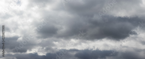 Dense dark gray storm clouds on overcast sky with light gaps and dramatic atmosphere before rain
