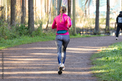 The woman is jogging in the autumn park.