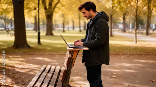 He is using the laptop standing up, using the back of the bench as a makeshift desk.
