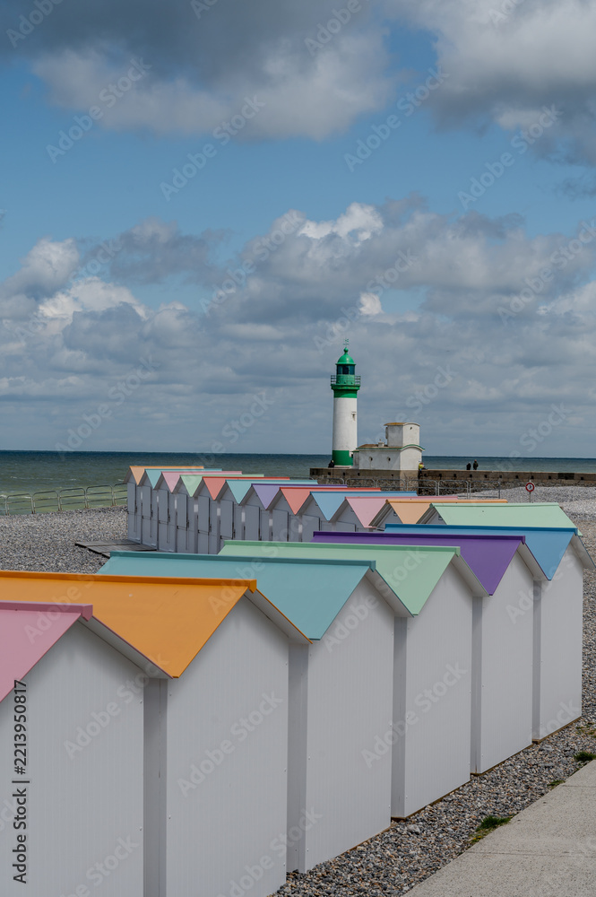 Fototapeta premium Views of ocean beach and colourful beach huts or cabins in Le Treport, seaside resort in Normandy, France, with white cliffs along English Channel, travel destination in France
