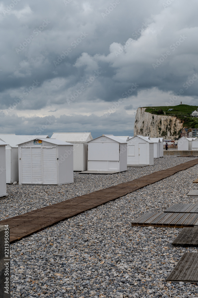 Fototapeta premium White bath huts in Mers-les-Bains, seaside town with 19th-century sea-bathing villas with colorful wooden balconies and white chalk cliffs, tourists destination in France