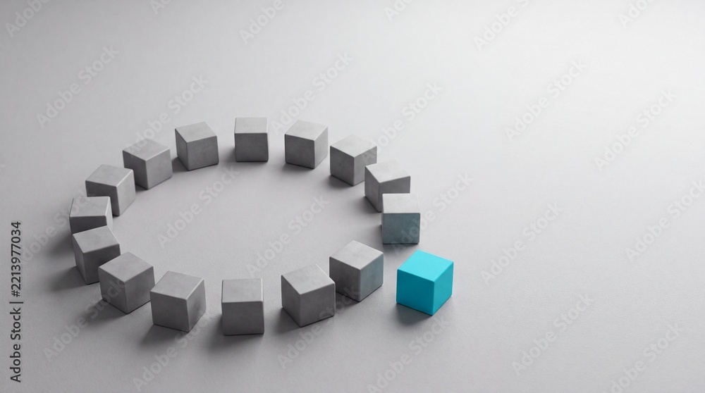 Fototapeta premium Unique bright blue cube standing out from a circle of identical grey concrete blocks on a minimalist surface, representing leadership, individuality, and core business concept metaphor.
