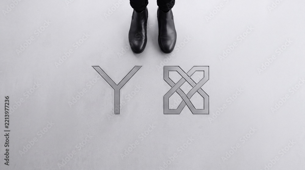 Fototapeta premium Top down view of a person standing before a Y junction symbol and a complex interlocking knot icon representing choice, strategic decision making, and conceptual path selection in business.