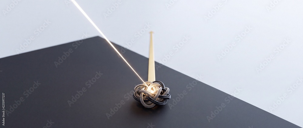Fototapeta premium Abstract conceptual image of a glowing beam of light hitting a tangled knot on a dark background, symbolizing focus, untangling complexity, and finding a solution in a bulk problem.