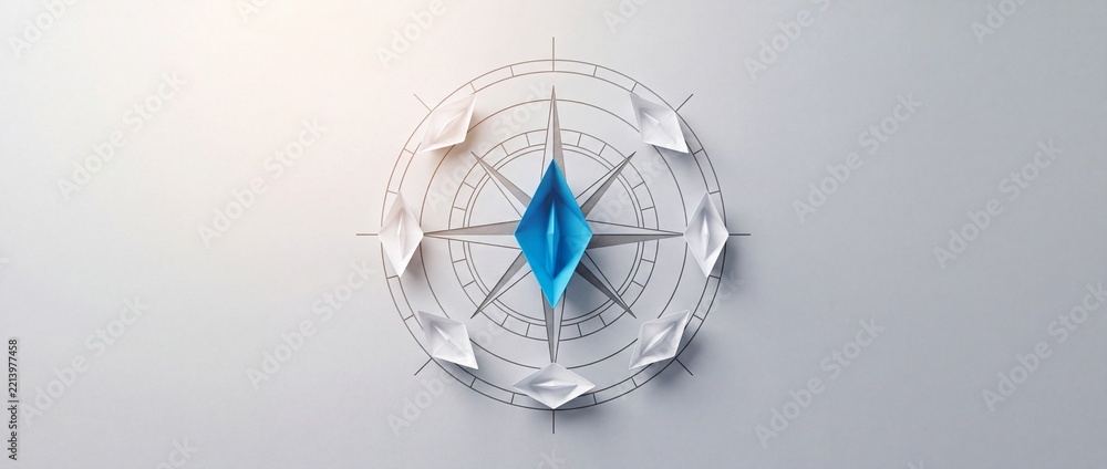 Fototapeta premium Blue paper boat leading white boats on a compass rose symbol, representing leadership, strategic navigation, business direction, and uniqueness in a minimalist conceptual composition.