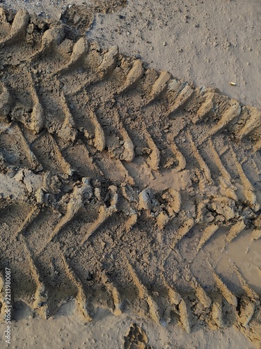 Top view close up of heavy machinery tire tracks pattern imprinted on wet muddy ground at a construction site.