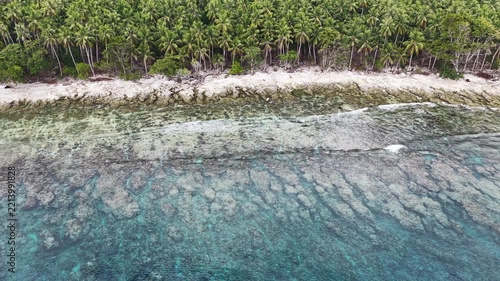 Calm seas bathe the beautiful coastline of the remote Maju Island in the Molucca Sea, Indonesia. A rugged, rocky reef surrounds this tropical paradise which few people ever visit.
