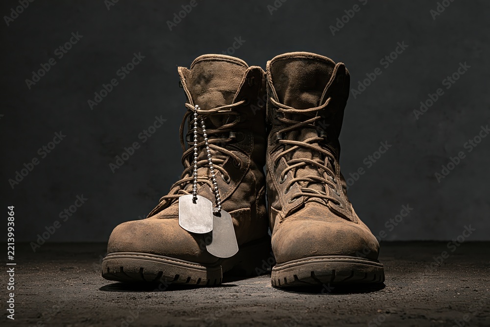 Fototapeta premium Military combat boots with hanging dog tags on concrete representing soldier service sacrifice
