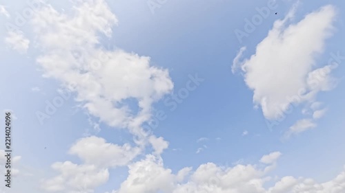 Cinematic time lapse of white puffy clouds sailing through a beautiful bright blue sunny sky. Perfect natural cloudscape background representing fresh air, freedom, good weather, and clean atmosphere.