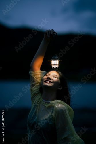 Young woman holding lantern with bright smile outdoors at night