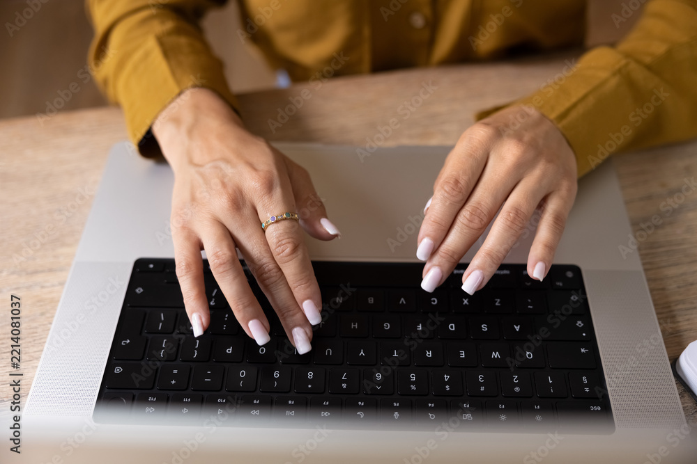 Fototapeta premium Female hands typing on laptop keyboard at office desk, closeup crop view. Businesswoman replying on business email, do remote work, lead digital communication, working online using modern technology