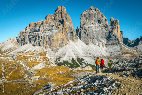 Hikers and high walls of Tre Cime peaks in background