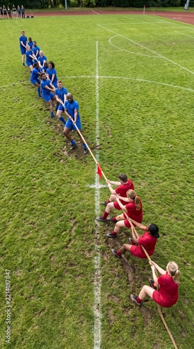 Group of athletes competing in a tug of war on a grassy field  