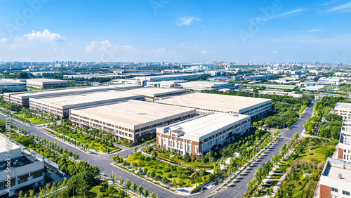 Aerial view of a modern industrial park with large buildings, green landscaping and paved roads under a clear blue sky.
