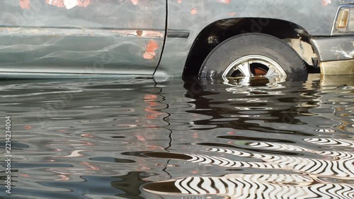 Close-Up of Rusted Vehicle Damaged and Submerged in Floodwater, Total Loss Car Reflecting Nearby Wreckage