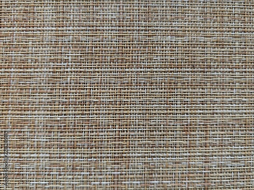 Woven texture background of a brown and beige mat, bamboo placemat, gunny sack cloth or wicker furniture, perfect as a neutral eco-friendly backdrop.