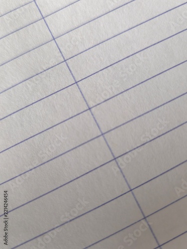 Close-up background of white lined notebook paper sheet with blue stripes at a diagonal angle.