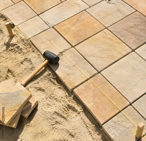Paving stones reseated in a sand bed with a rubber mallet and levelling string line on a public square