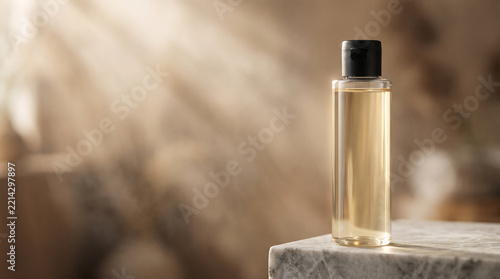Clear cosmetic bottle on marble surface with soft sunlight