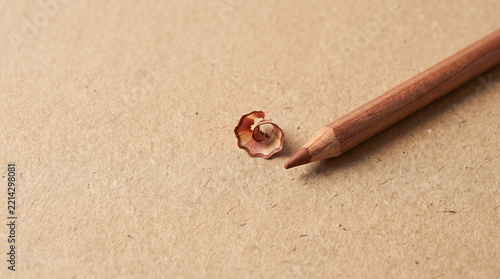 Brown pencil with shavings on textured paper background