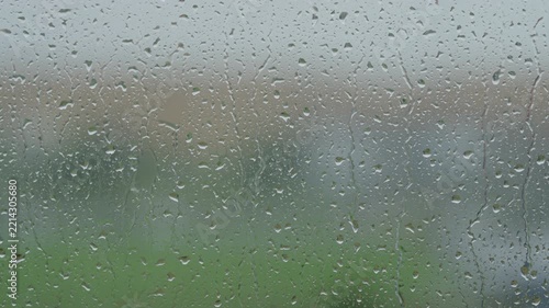 Rain drop hitting window glass and sliding down