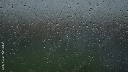 Rain drop hitting window glass and sliding down