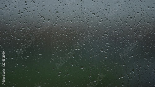 Rain drop hitting window glass and sliding down