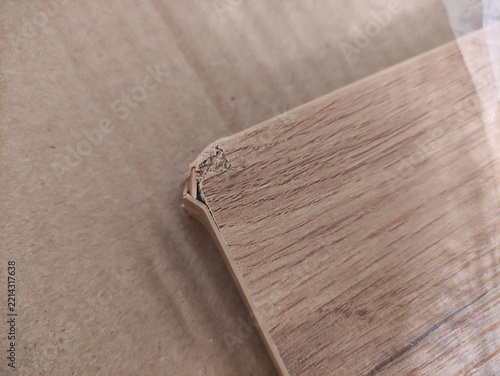 Close up of damaged chipboard corner with chipped edge and wood pattern on cardboard