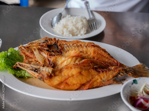 Deep fried whole sea bass with fish sauce served on a plate with rice