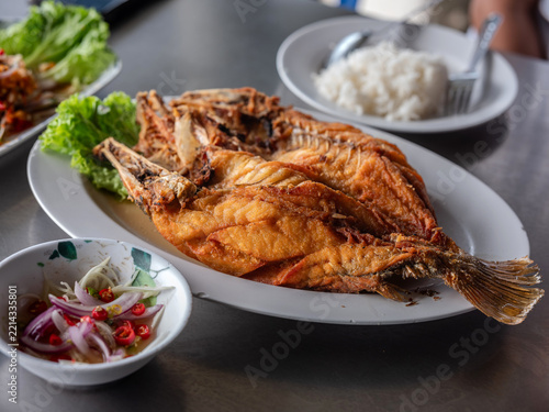 Deep fried whole sea bass with fish sauce served on a plate with rice