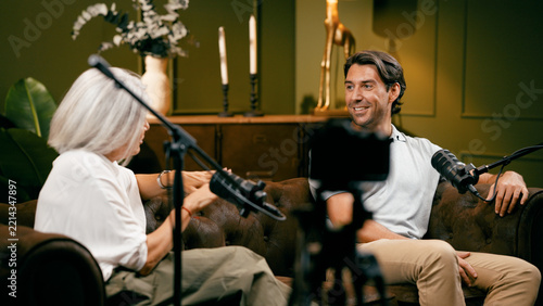 Man and woman hosting an audio podcast, creating digital content for online streaming, using microphones in a professional setting
