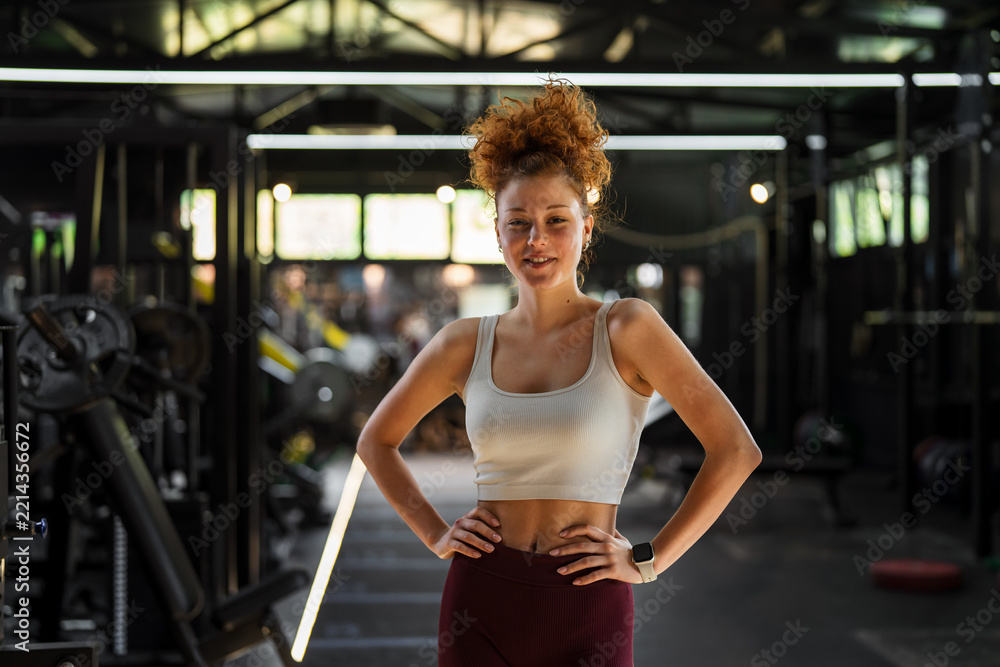Naklejka premium Young fit woman standing in modern gym posing after workout