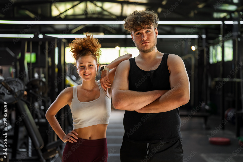 Naklejka premium Young man and woman posing for fitness motivation at gym