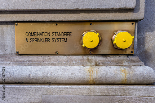 Yellow fire connection caps on a brass standpipe wall sign