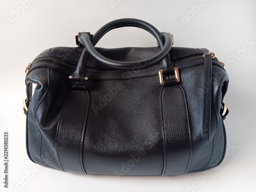 Close up of black leather woman handbag with a round top handle, zip top and gold hardware isolated on a white background.