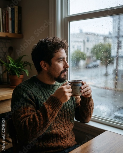 Man in Cozy Sweater Drinking Hot Coffee by Rainy Window
