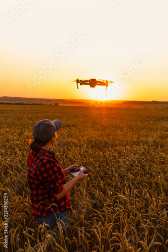 Woman farmer with drone on a wheat field. Smart farming and precision agriculture.