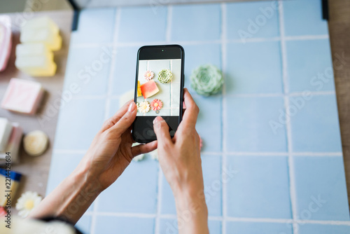 Closeup of a woman using smartphone taking content image of handmade soap for small business marketing and social media