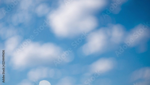 Soft white clouds floating in a bright blue sky with bokeh effect during daytime