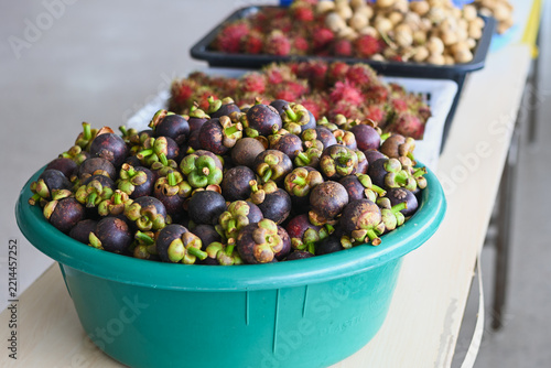 Fresh dark purple mangosteens piled in a green basin