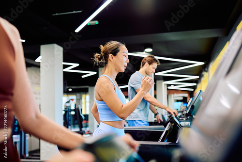 Fotografie Group of diverse people exercising in a modern gym, walking and running on tread