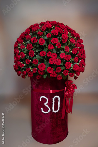 Impressive floral photo zone setup for 30th birthday anniversary celebration.Large luxurious red rose floral arrangement with number 30 stand in event hall.