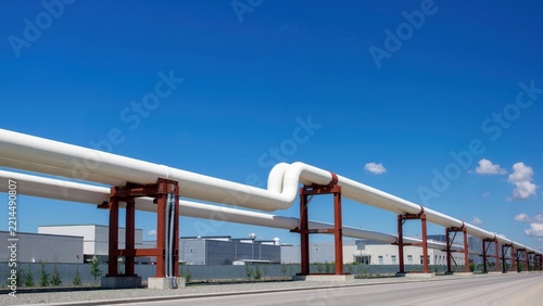Elevated insulated pipeline on red steel supports in an industrial zone. District heating and thermal utility distribution system with expansion loop