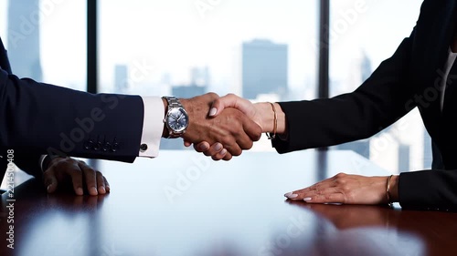Business Agreement Handshake: A professional handshake between two business people sealing a deal, symbolizing trust and partnership against a cityscape backdrop.
