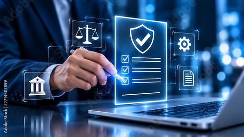 Businessman using a stylus to check digital compliance documents on a virtual interface with icons of law scales, shield protection, and regulation over a laptop in a modern corporate office.