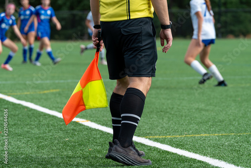 Soccer sideline referee wearing black shorts and holding a flag from the sideline_