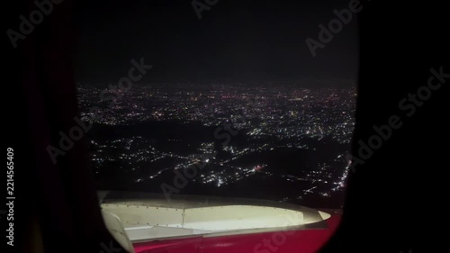 Bright lights from cityscape seen from plane window on a night flight. Travel concept of airplane transport.