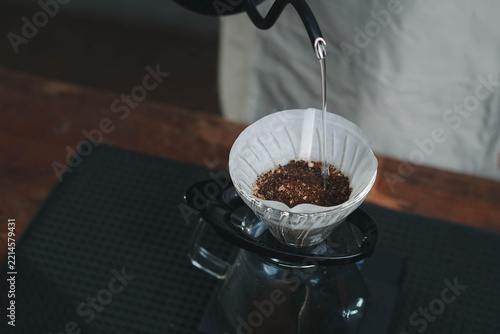 Fotografie Barista pours hot water from a kettle over ground coffee in a filter