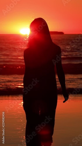 Attractive Asian woman enjoys a walk on the beach at sunset in Southern California. Slow Motion. Vertical Video.