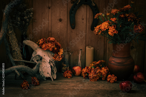 Mystical autumnal atmospheric set. Witchy altar with animal horny skull, marigolds, dried herbs and horseshoe for Samhain or day of the dead.